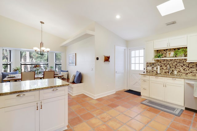 kitchen with white cabinets, plenty of natural light, sink, and lofted ceiling with skylight