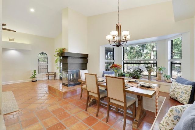 dining room with a high ceiling, a chandelier, tile patterned flooring, and a multi sided fireplace