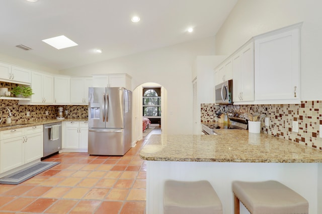 kitchen featuring white cabinetry, kitchen peninsula, appliances with stainless steel finishes, and lofted ceiling