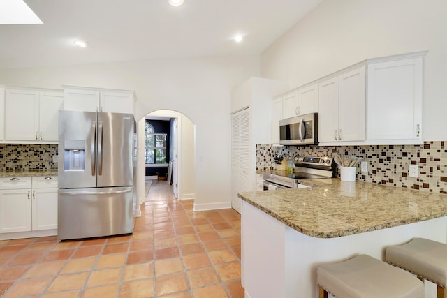 kitchen with kitchen peninsula, white cabinetry, appliances with stainless steel finishes, and tasteful backsplash