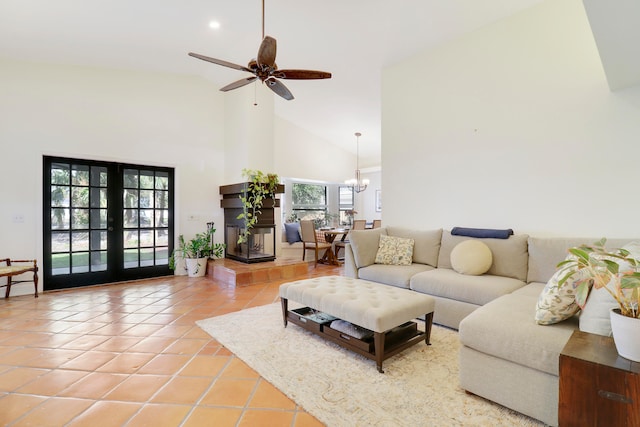 living room with ceiling fan with notable chandelier, french doors, tile patterned floors, and high vaulted ceiling