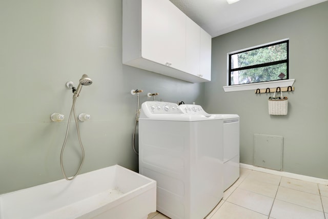 washroom featuring washing machine and dryer, cabinets, and light tile patterned floors