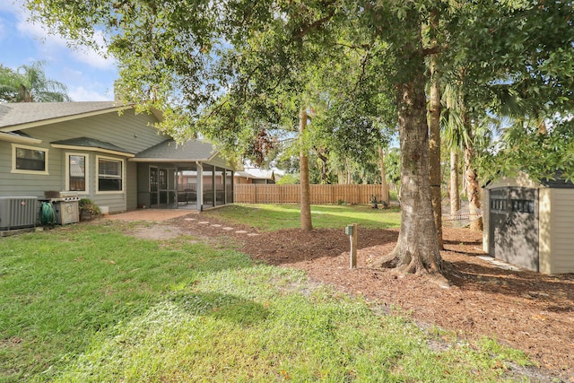 view of yard with central air condition unit, a sunroom, and a storage shed