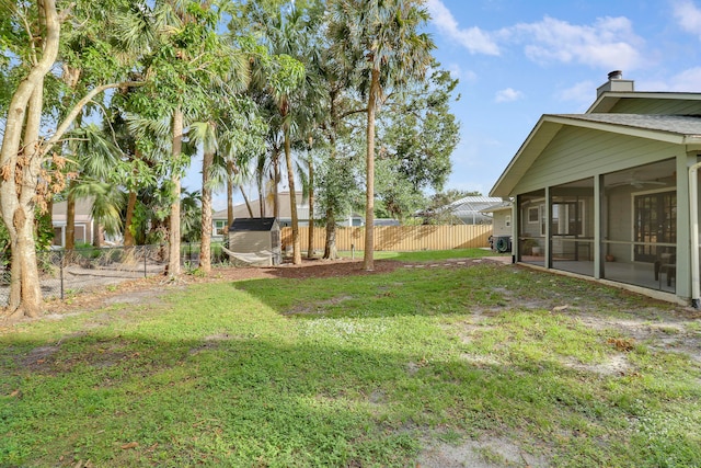 view of yard featuring ceiling fan and a sunroom