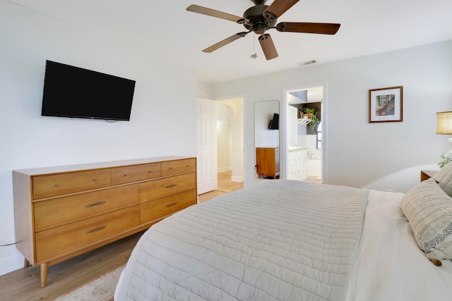 bedroom with ceiling fan, connected bathroom, and light wood-type flooring