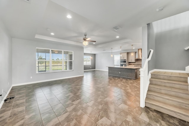 11461 SW Lyra Dr, Port Saint Lucie, FL 34987 - unfurnished living room featuring a tray ceiling, recessed lighting, a ceiling fan, stairs, and baseboards