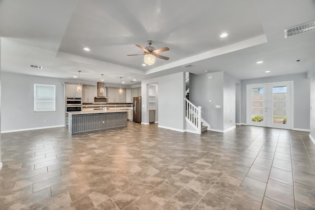 11461 SW Lyra Dr, Port Saint Lucie, FL 34987 - unfurnished living room featuring a raised ceiling, stairway, ceiling fan, baseboards, and recessed lighting