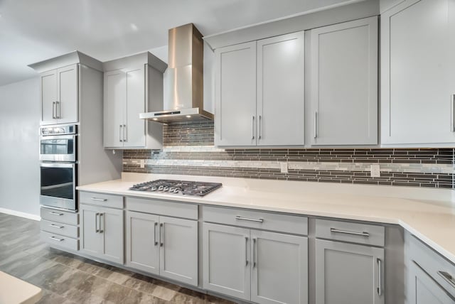11461 SW Lyra Dr, Port Saint Lucie, FL 34987 - kitchen featuring wall chimney range hood, appliances with stainless steel finishes, gray cabinets, and tasteful backsplash