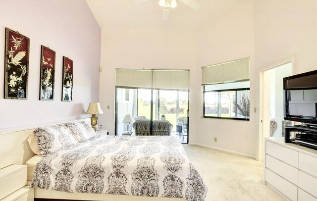 carpeted bedroom featuring ceiling fan, access to exterior, and a towering ceiling