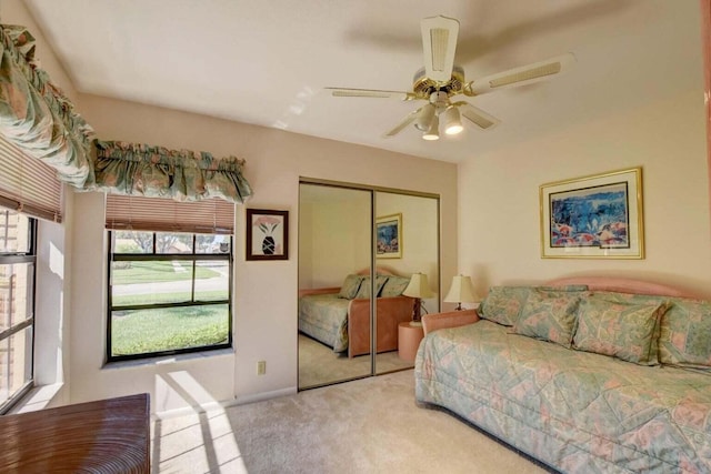 bedroom featuring ceiling fan, light colored carpet, and a closet