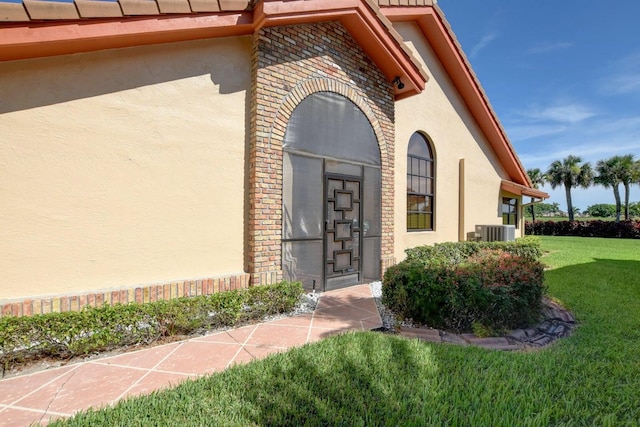 entrance to property featuring cooling unit and a yard