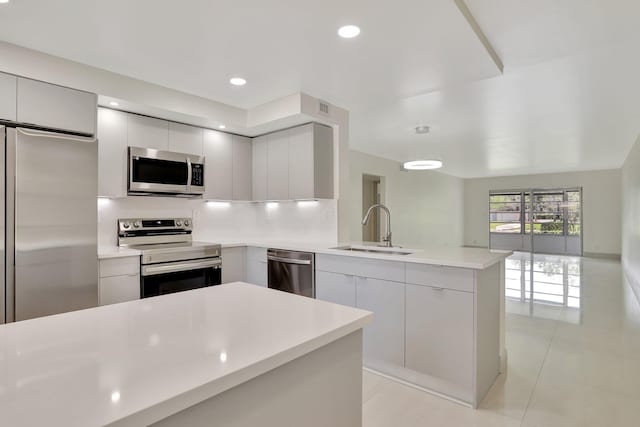 kitchen with kitchen peninsula, sink, light tile patterned flooring, and stainless steel appliances