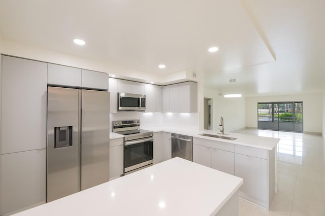 kitchen with kitchen peninsula, appliances with stainless steel finishes, sink, and light tile patterned floors