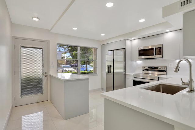 kitchen featuring stainless steel appliances, light tile patterned floors, sink, and kitchen peninsula