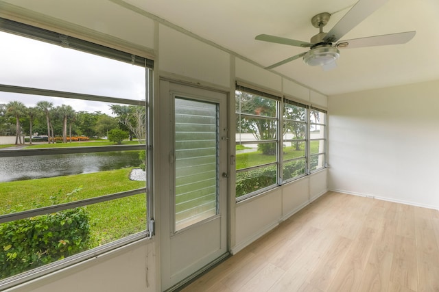 unfurnished sunroom with ceiling fan, a water view, and a healthy amount of sunlight