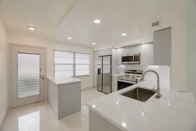 kitchen featuring kitchen peninsula, sink, light tile patterned flooring, and stainless steel appliances