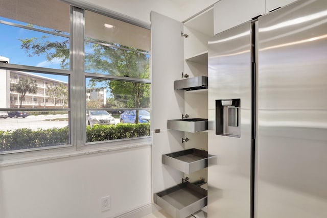 kitchen featuring stainless steel refrigerator with ice dispenser and white cabinets