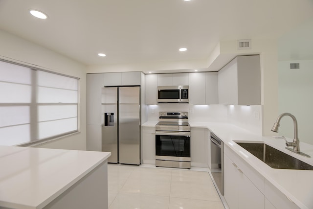 kitchen with stainless steel appliances, white cabinets, sink, and light tile patterned floors