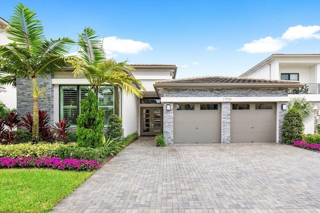 17056 Cappuccino Way, Boca Raton, FL 33496 - view of front of home with french doors, a garage, stucco siding, decorative driveway, and stone siding