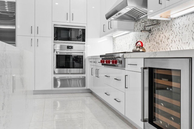 kitchen featuring wine cooler, white cabinetry, wall chimney range hood, and appliances with stainless steel finishes