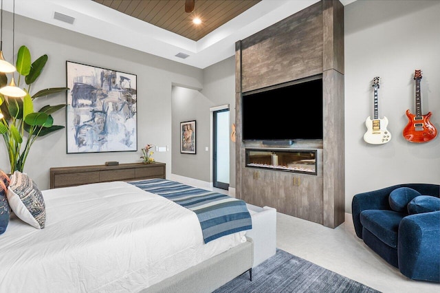 carpeted bedroom featuring wood ceiling, a fireplace, and a tray ceiling