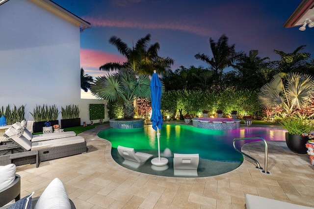 pool at dusk featuring a patio area and an in ground hot tub