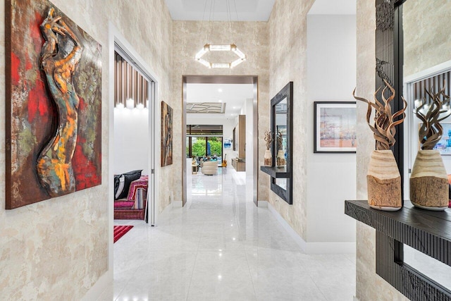 corridor with a towering ceiling and a notable chandelier