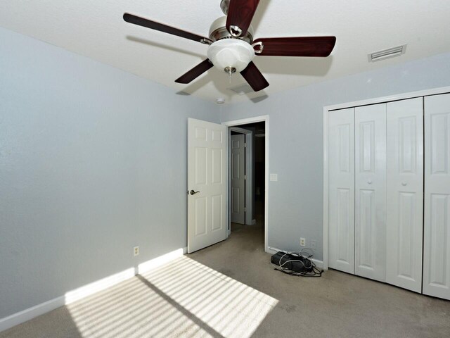 unfurnished bedroom featuring light colored carpet, ceiling fan, and a closet