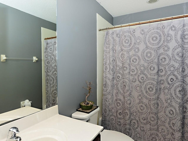 bathroom featuring vanity, walk in shower, a textured ceiling, and toilet