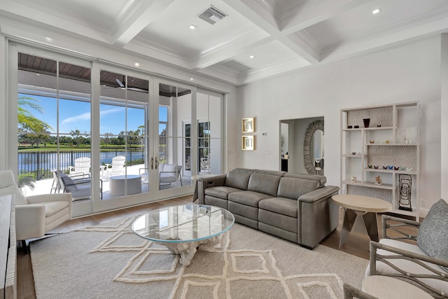 living room with beamed ceiling, a water view, coffered ceiling, and light hardwood / wood-style flooring