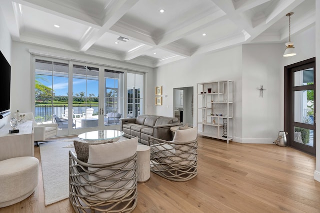 living room with a wealth of natural light, beamed ceiling, a water view, and light hardwood / wood-style flooring