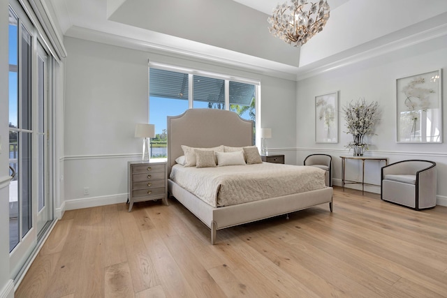 bedroom featuring light wood-type flooring, a tray ceiling, a notable chandelier, and crown molding