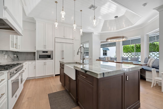 kitchen with white cabinetry, light hardwood / wood-style flooring, high end white range oven, and custom exhaust hood