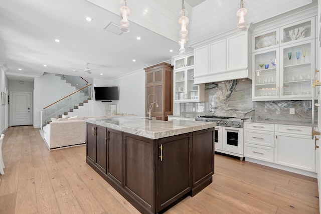 kitchen featuring light hardwood / wood-style floors, white cabinetry, light stone counters, double oven range, and hanging light fixtures