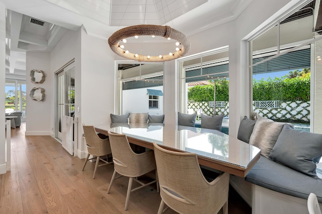 dining area with ornamental molding, light hardwood / wood-style flooring, and a healthy amount of sunlight