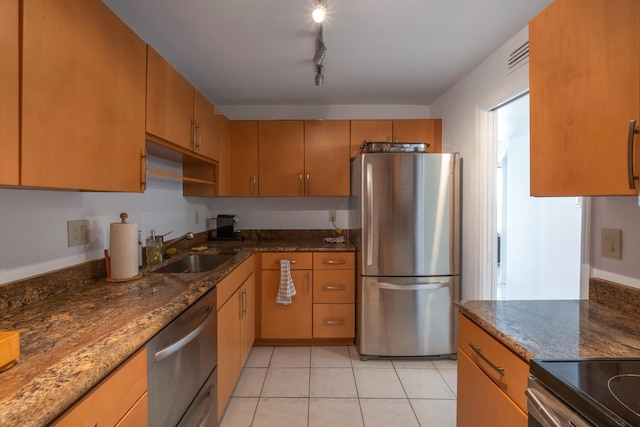 kitchen featuring sink, dark stone counters, stainless steel appliances, and light tile patterned floors