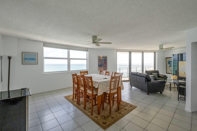 tiled dining room with a textured ceiling, a water view, and ceiling fan