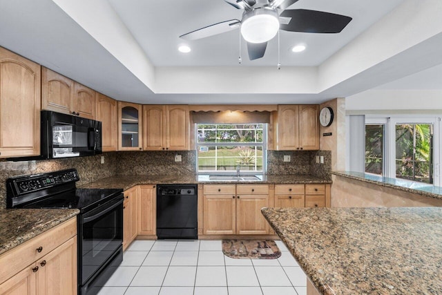 kitchen featuring sink, tasteful backsplash, dark stone counters, light tile patterned floors, and black appliances