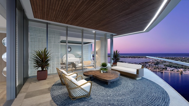 balcony at dusk featuring a water view