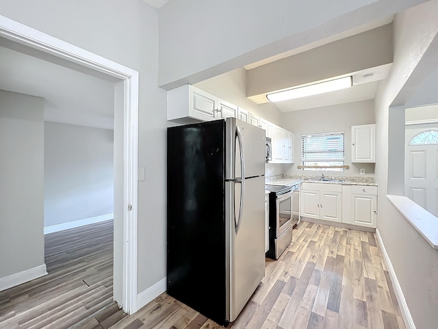 kitchen with light wood-type flooring, appliances with stainless steel finishes, sink, and white cabinets