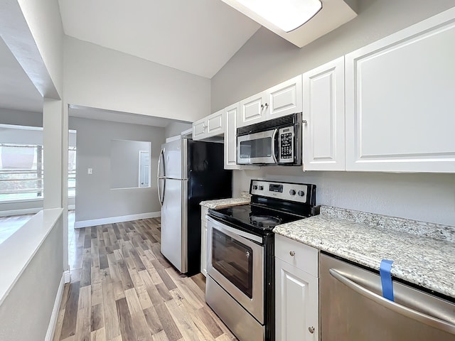 kitchen featuring white cabinetry, light wood-type flooring, stainless steel appliances, and vaulted ceiling