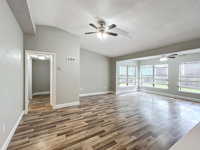 unfurnished living room with ceiling fan, wood-type flooring, a textured ceiling, and lofted ceiling