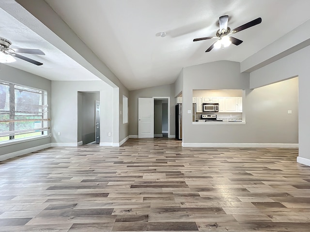 unfurnished living room with light hardwood / wood-style floors, ceiling fan, and vaulted ceiling