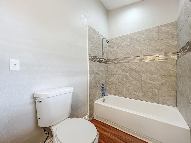 bathroom featuring toilet, tiled shower / bath combo, and hardwood / wood-style floors