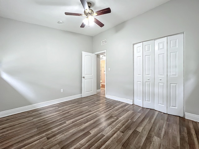 unfurnished bedroom featuring dark wood-type flooring, a closet, and ceiling fan