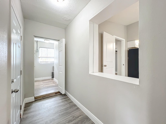 hallway with hardwood / wood-style floors and a textured ceiling