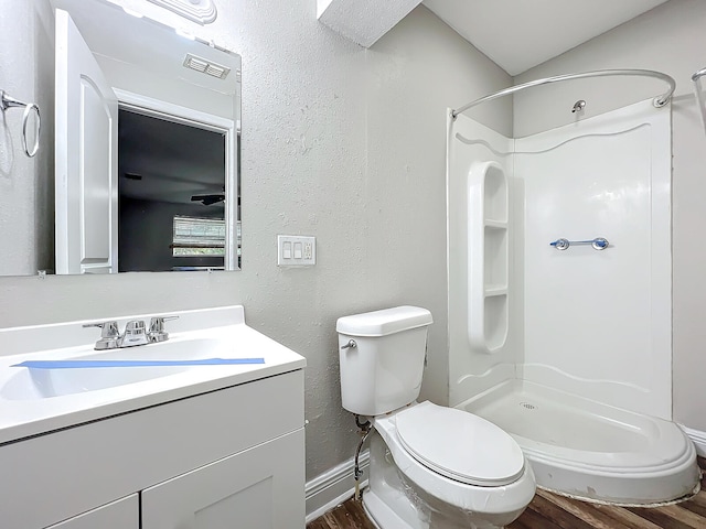 bathroom with hardwood / wood-style floors, walk in shower, vanity, and toilet