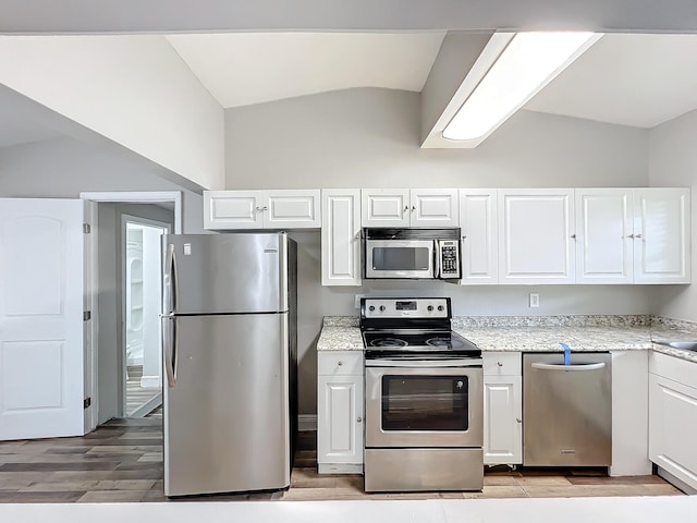 kitchen featuring white cabinetry, light wood-type flooring, stainless steel appliances, and lofted ceiling