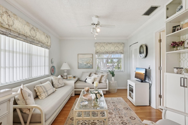 living room featuring a textured ceiling, light hardwood / wood-style floors, ornamental molding, and ceiling fan