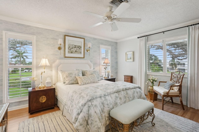 bedroom featuring ornamental molding, a textured ceiling, ceiling fan, and light hardwood / wood-style flooring